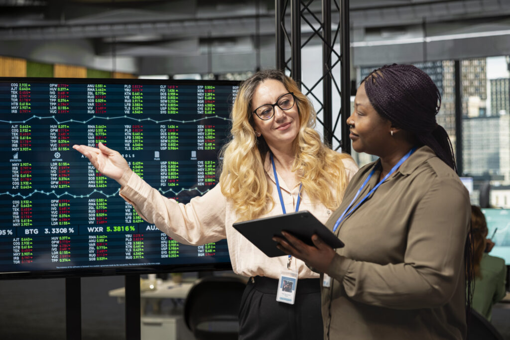 How to Trade Smart, Manage Risk, and Day Trading Guide 2 diverse businesswomen working side by side to review data on tv monitor